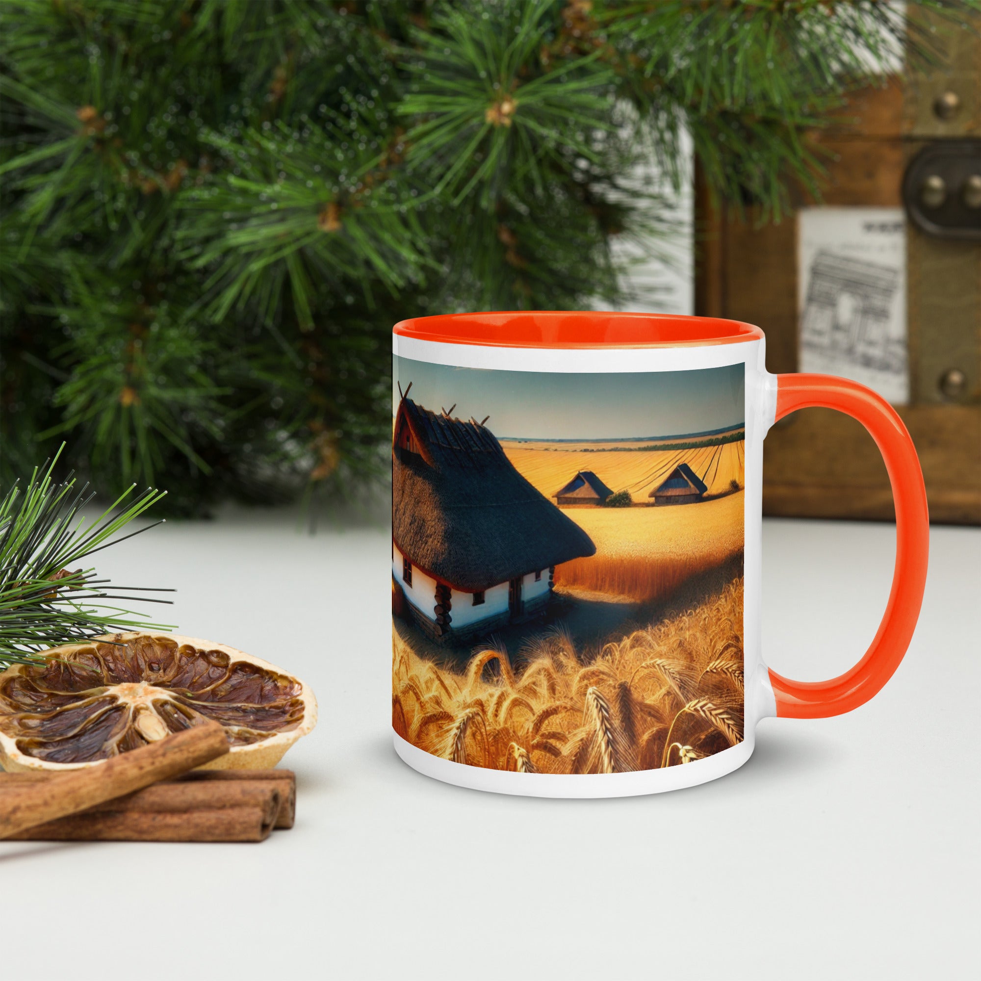 Ukrainian cottage in wheat field mug with orange rim and handle, surrounded by dried citrus and pine, embodying rustic charm.
