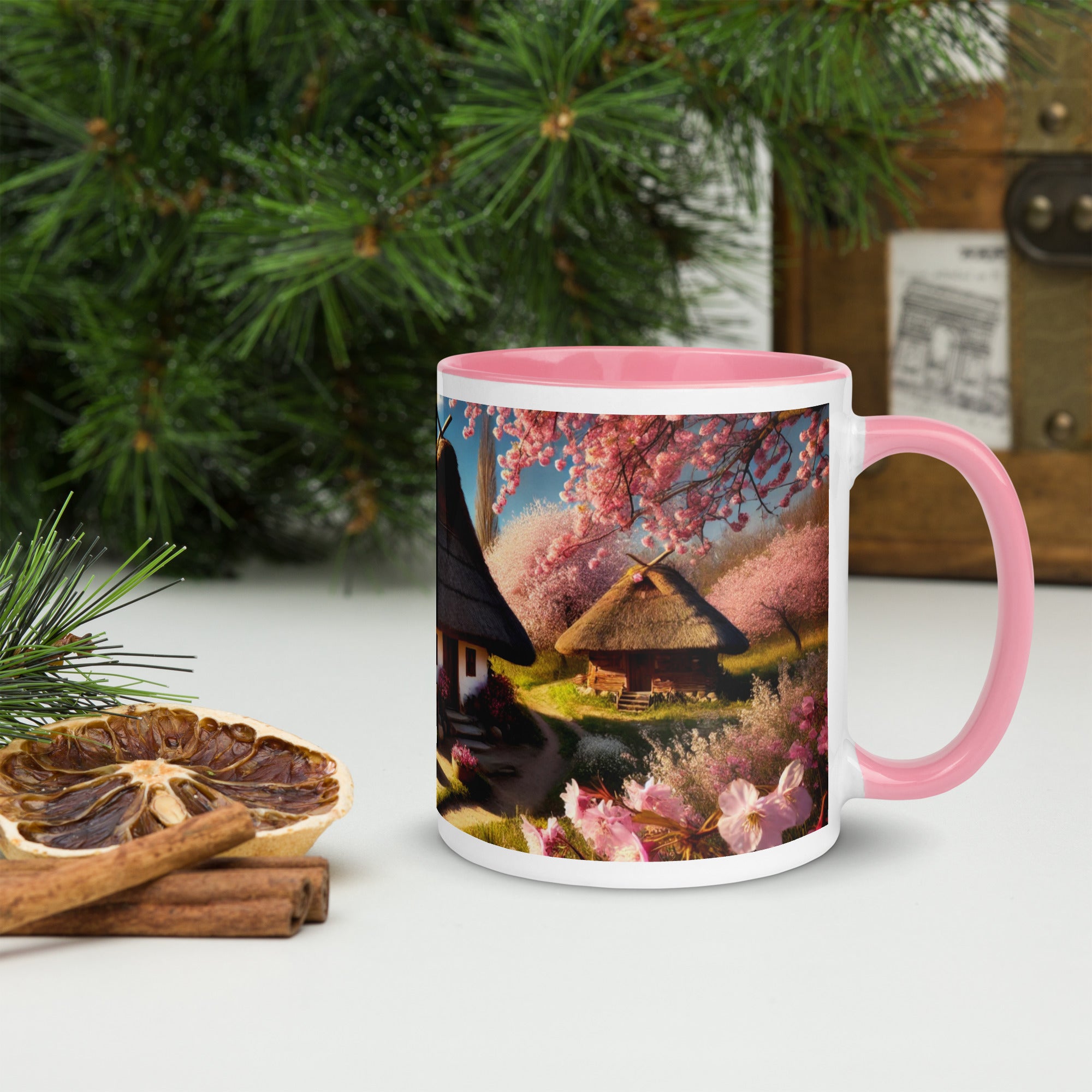 Ceramic mug with Ukrainian cottage art, pink rim and handle, surrounded by pine branches and dried citrus slices.