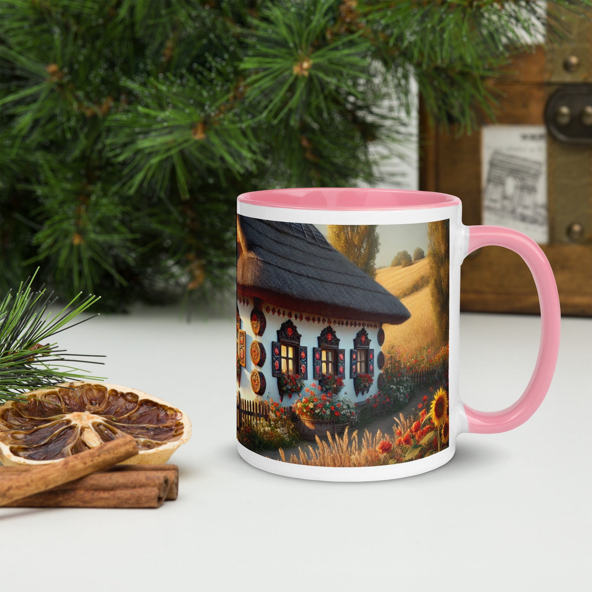 Ceramic mug featuring Ukrainian cottage with scenic yard, pink rim and handle, surrounded by pine and rustic decor elements.