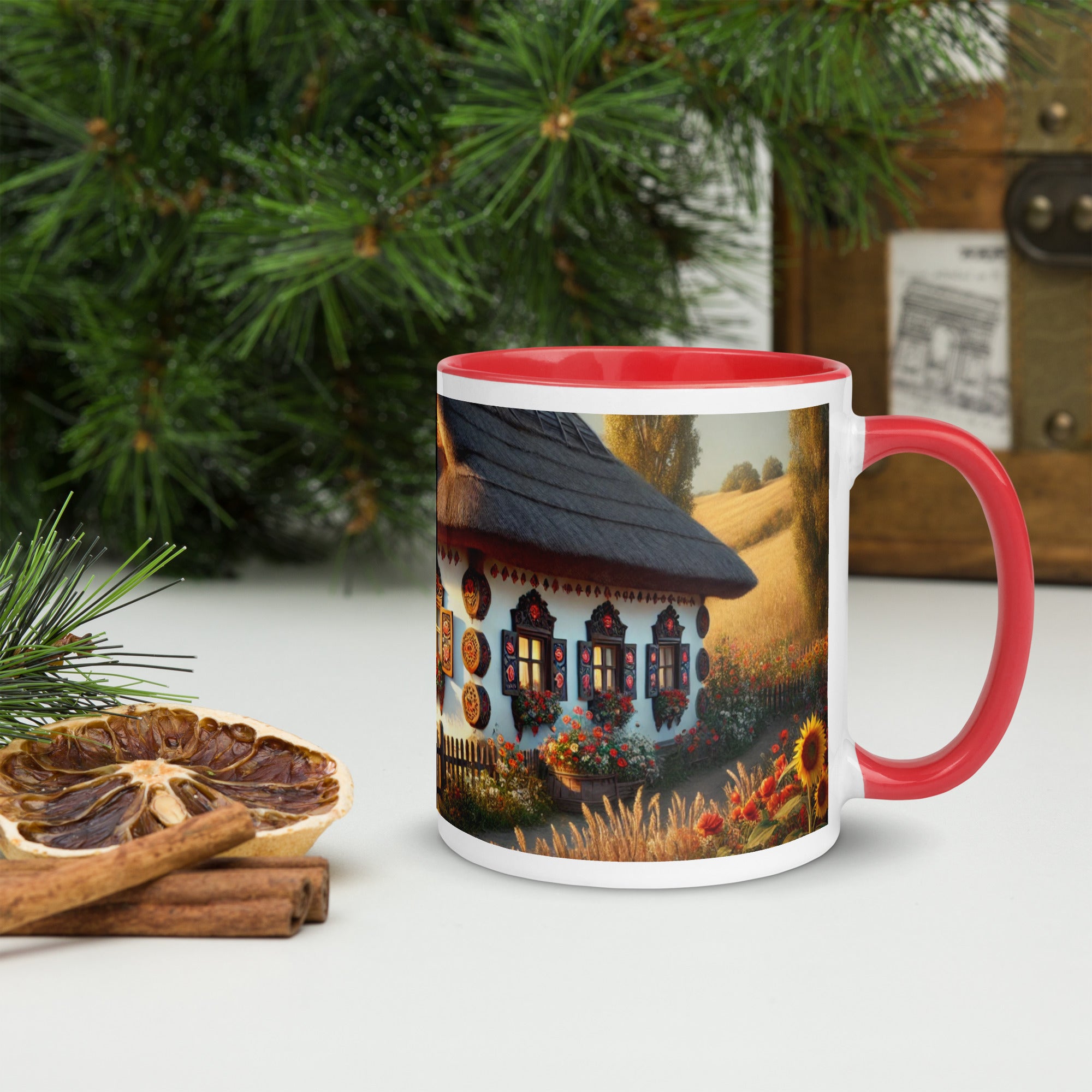 Ukrainian cottage ceramic mug with scenic yard design, red interior and handle, surrounded by greenery and dried citrus slices.