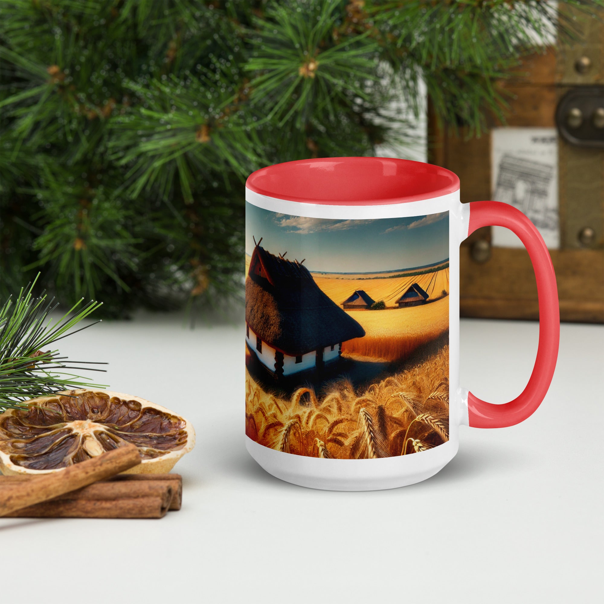 Ceramic mug with Ukrainian cottage and wheat field design, featuring red rim and handle, set on a rustic table with pine and spices.