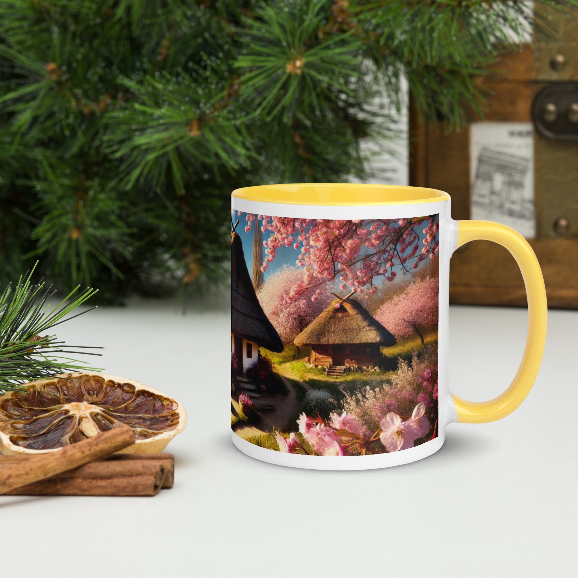 Ukrainian cottage mug with cherry orchard design, yellow rim and handle, surrounded by pine and dried citrus.