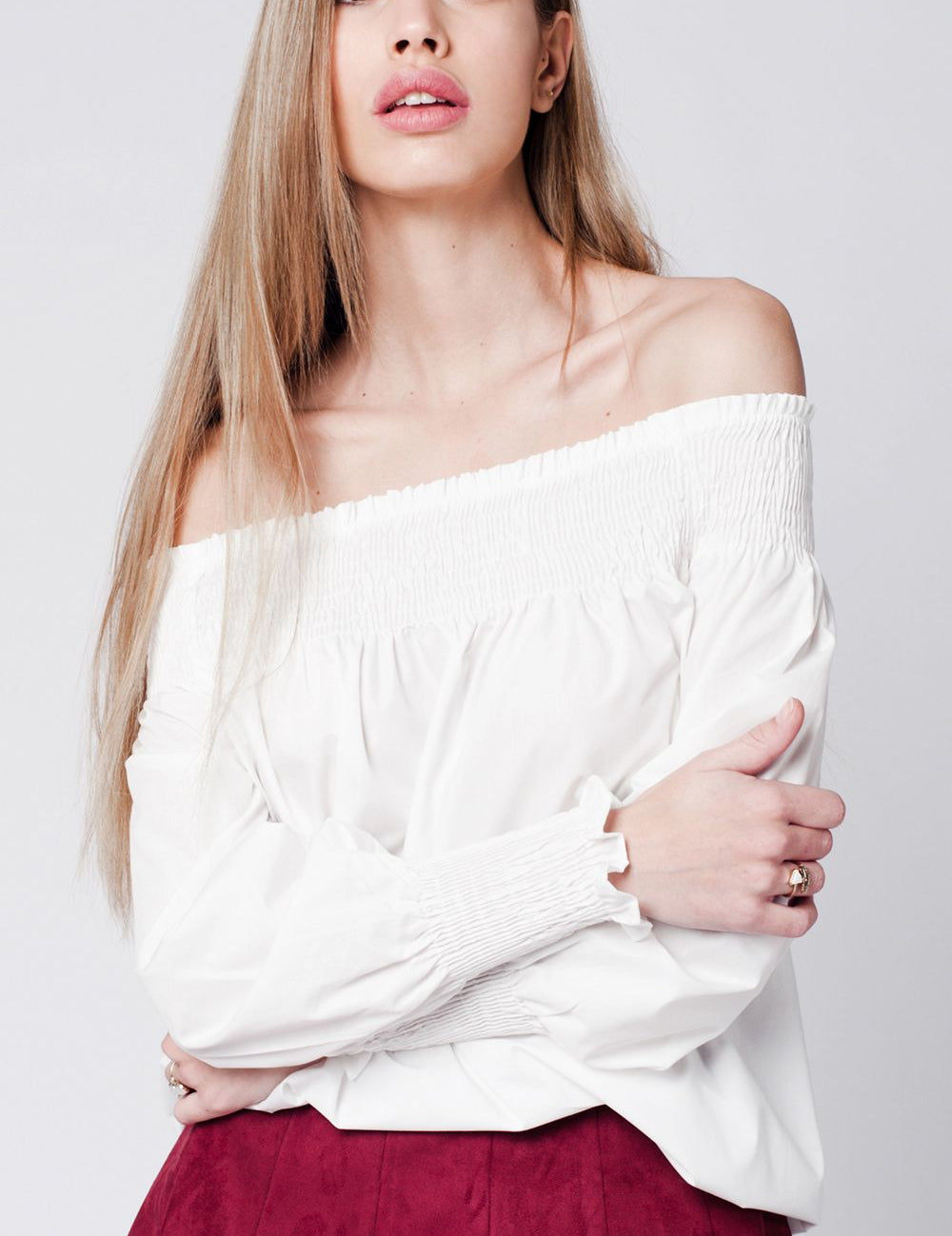 White poplin shoulder top with open shoulders, styled on model, highlighting crisp minimalism and modern silhouette.