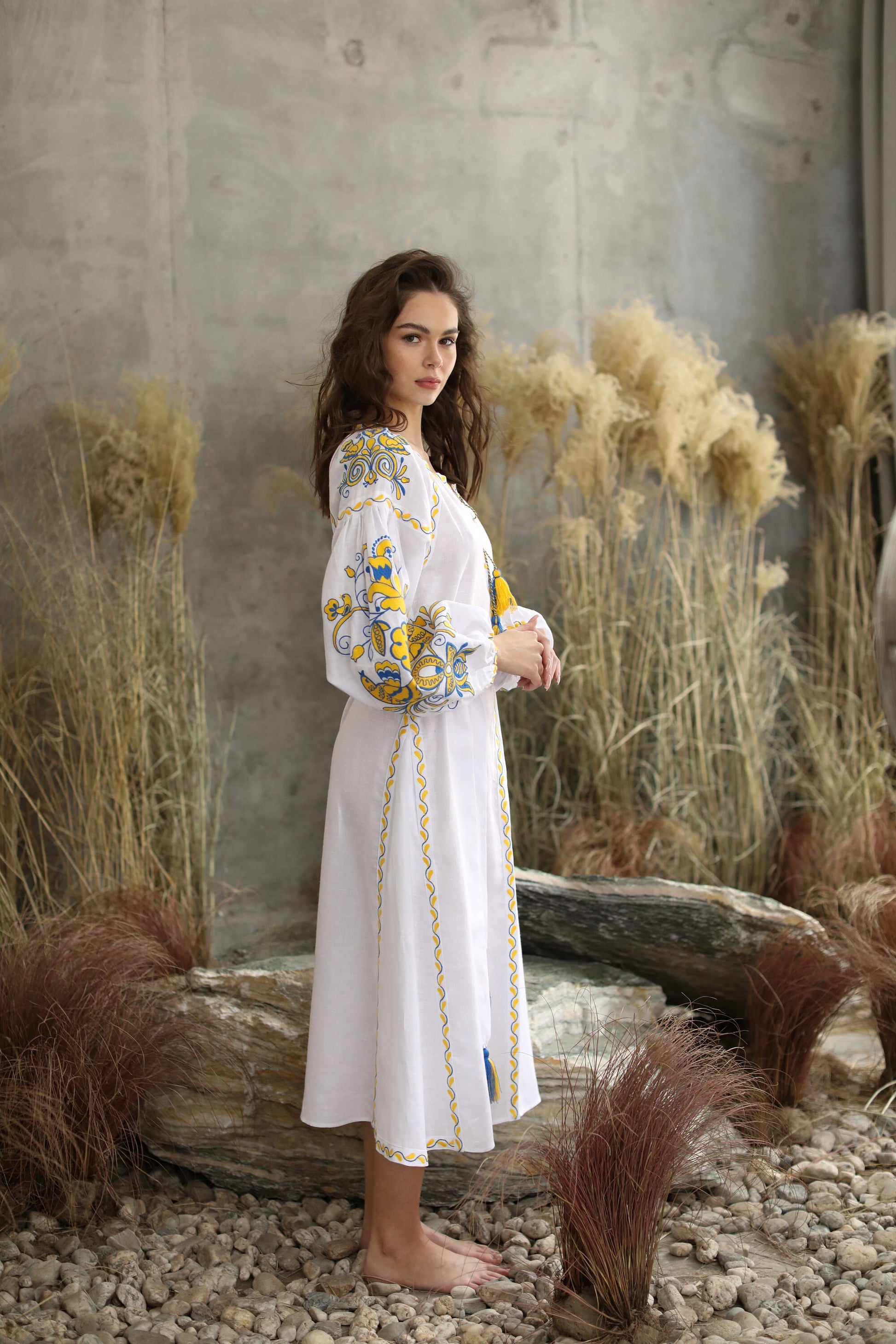 Model wearing white linen embroidered 'Victory' wedding dress in Ukrainian Vyshyvanka boho style.