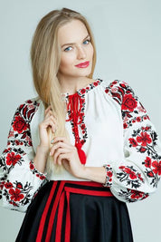 Woman wearing white embroidered Ukrainian sorochka blouse with red and black cross-stitch patterns.