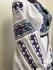 Women's embroidered Ukrainian vyshyvanka blouse with traditional cross-stitch on white homespun fabric, featuring vibrant floral patterns