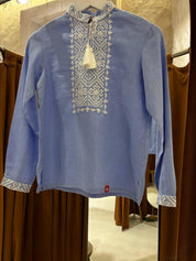 Blue linen shirt with white embroidered Ukrainian motifs, long sleeves, displayed against a neutral background.