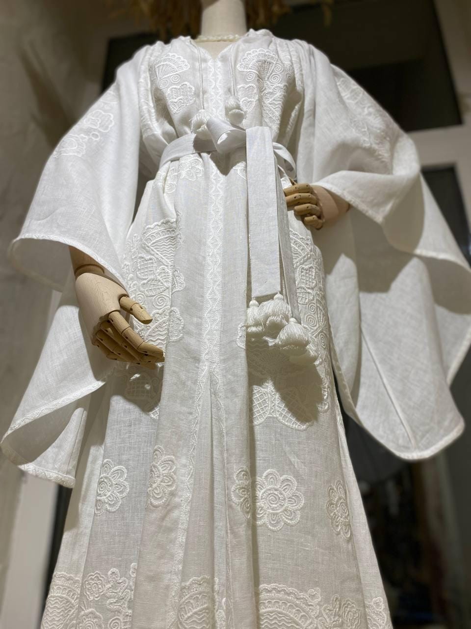 White linen wedding dress with Ukrainian embroidery in boho style, ideal gift for her, featuring subtle floral patterns on mannequin.