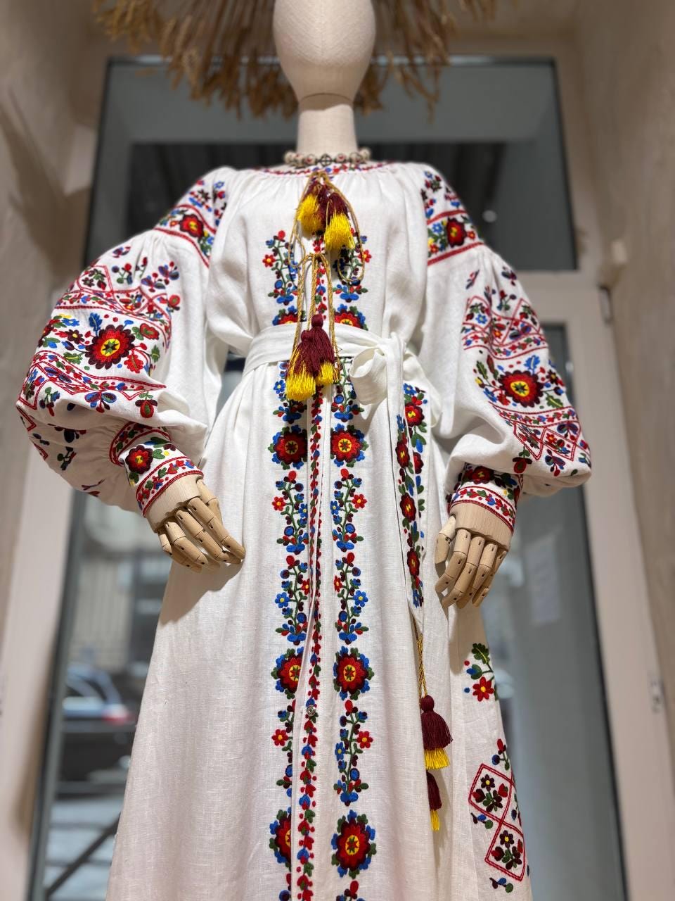 White linen embroidered wedding dress in Ukrainian Vyshyvanka boho style with colorful folk patterns and flowing silhouette.