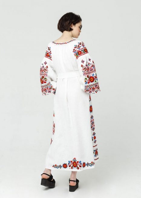 Back view of a white linen embroidered wedding dress in Ukrainian Vyshyvanka boho style, featuring colorful folk patterns.