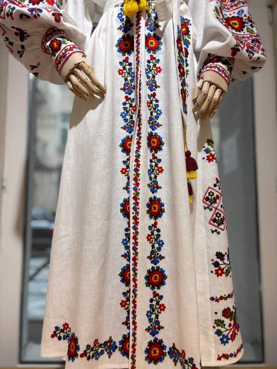 Boho style Ukrainian vyshyvanka wedding dress with colorful embroidery on white linen, showcasing traditional folk patterns.