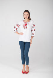 Woman wearing white linen vyshyvanka blouse with red Ukrainian embroidery, showcasing traditional folk style and modern elegance.