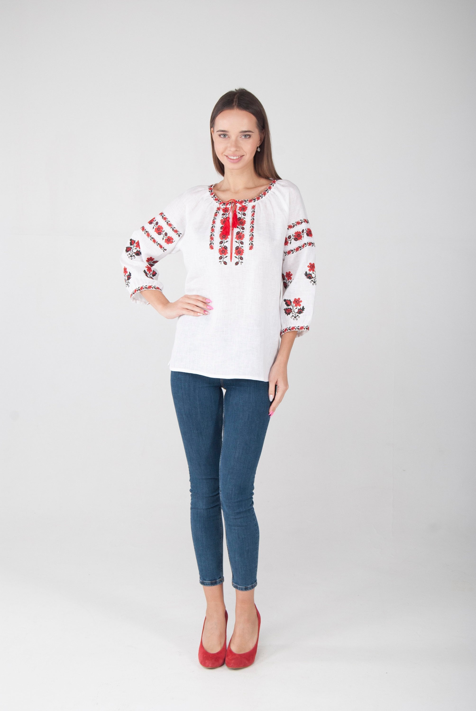 Woman wearing white linen vyshyvanka blouse with red Ukrainian embroidery, showcasing traditional folk style and modern elegance.