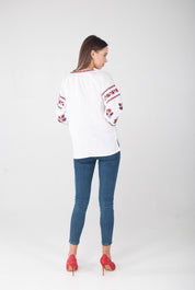 Woman wearing white linen vyshyvanka blouse with red embroidery, showcasing Ukrainian folk style.
