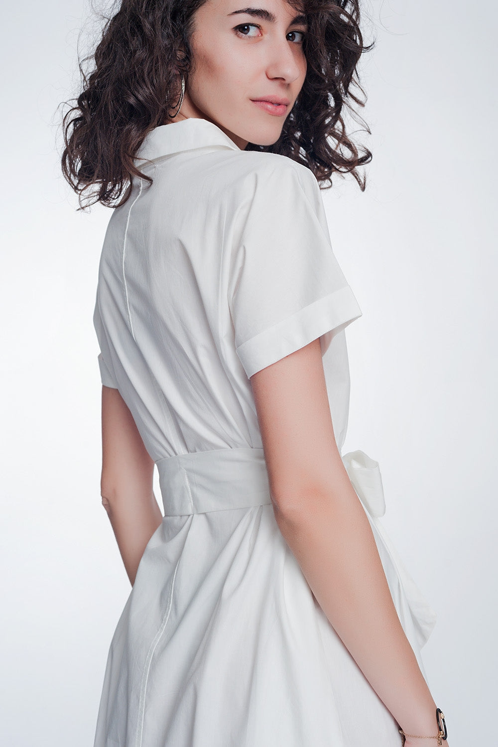 Back view of woman wearing a white Calviera Belted Poplin Shirt Dress with tailored short sleeves and a waist-cinching belt.