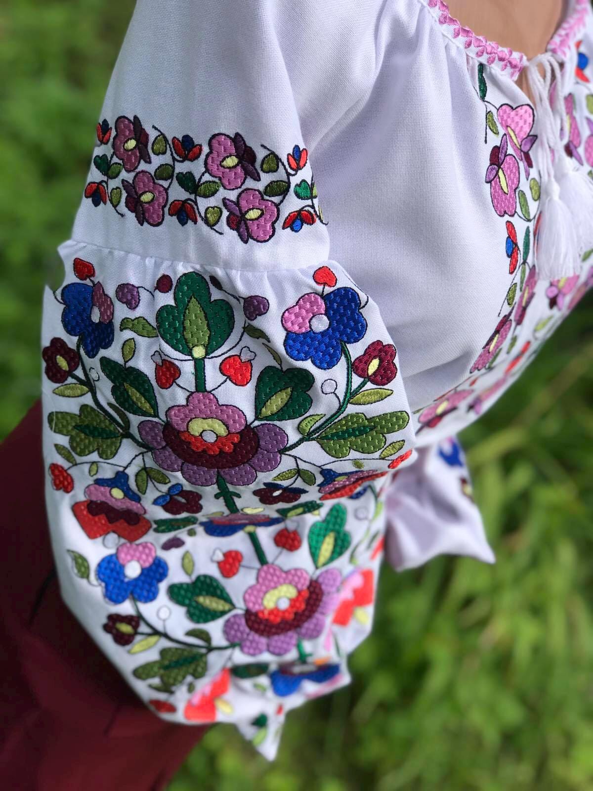 White Ukrainian embroidered blouse with colorful floral motifs on homespun fabric, showcasing traditional women's vyshyvanka design.