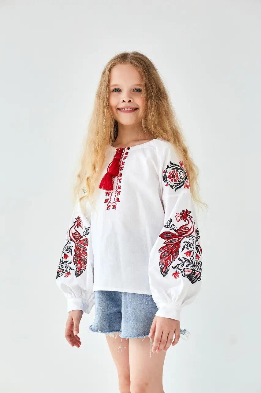 Girl wearing a white Ukrainian Phoenix embroidered shirt with red and black motifs, made of 100% cotton.