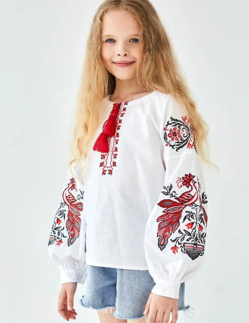 Girl wearing white Ukrainian embroidered shirt with red and black Slavic motifs, 100% cotton, perfect for everyday wear or special occasions.