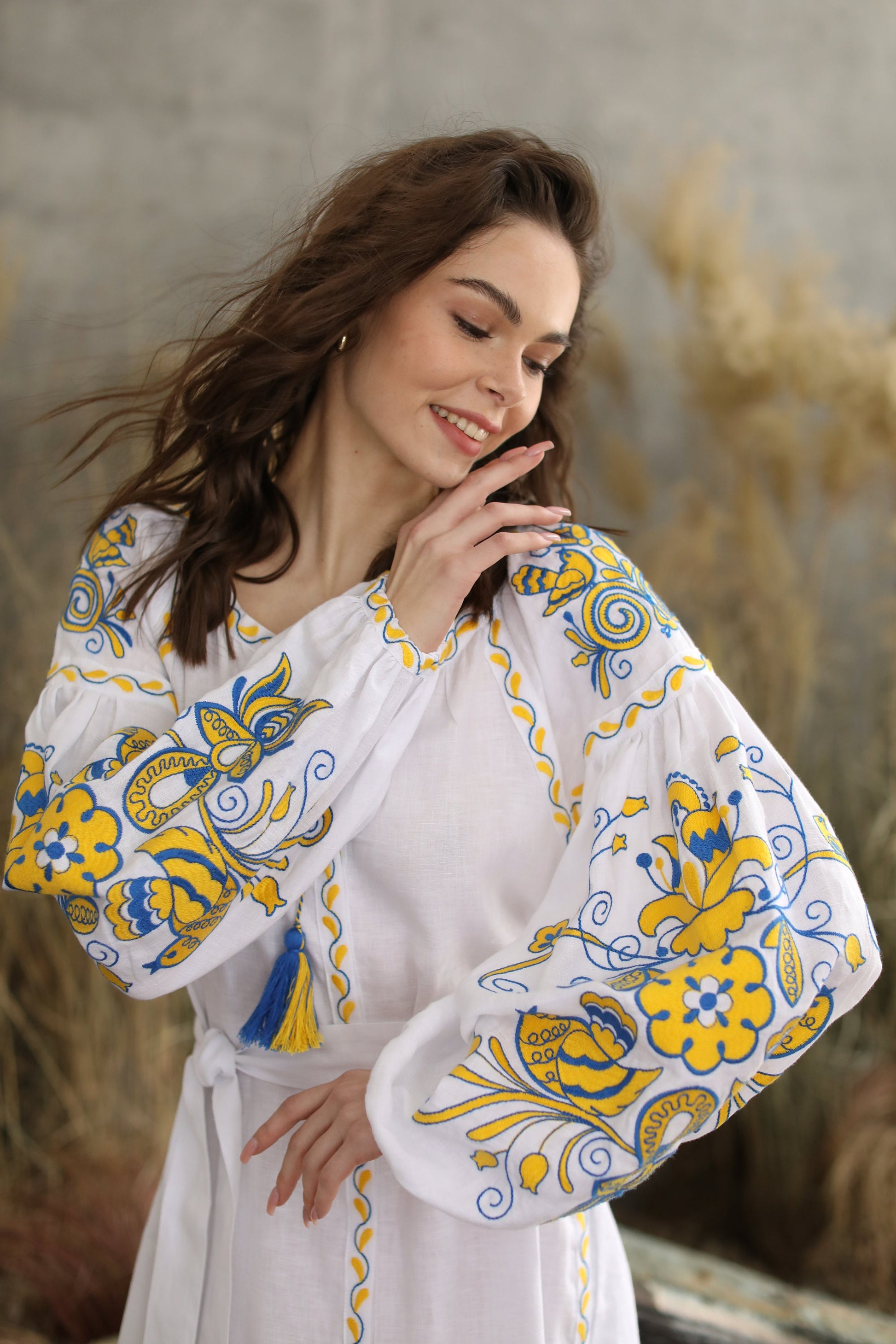 Ukrainian Vyshyvanka boho style wedding dress with yellow and blue embroidery on sleeves, worn by a woman in a natural setting.