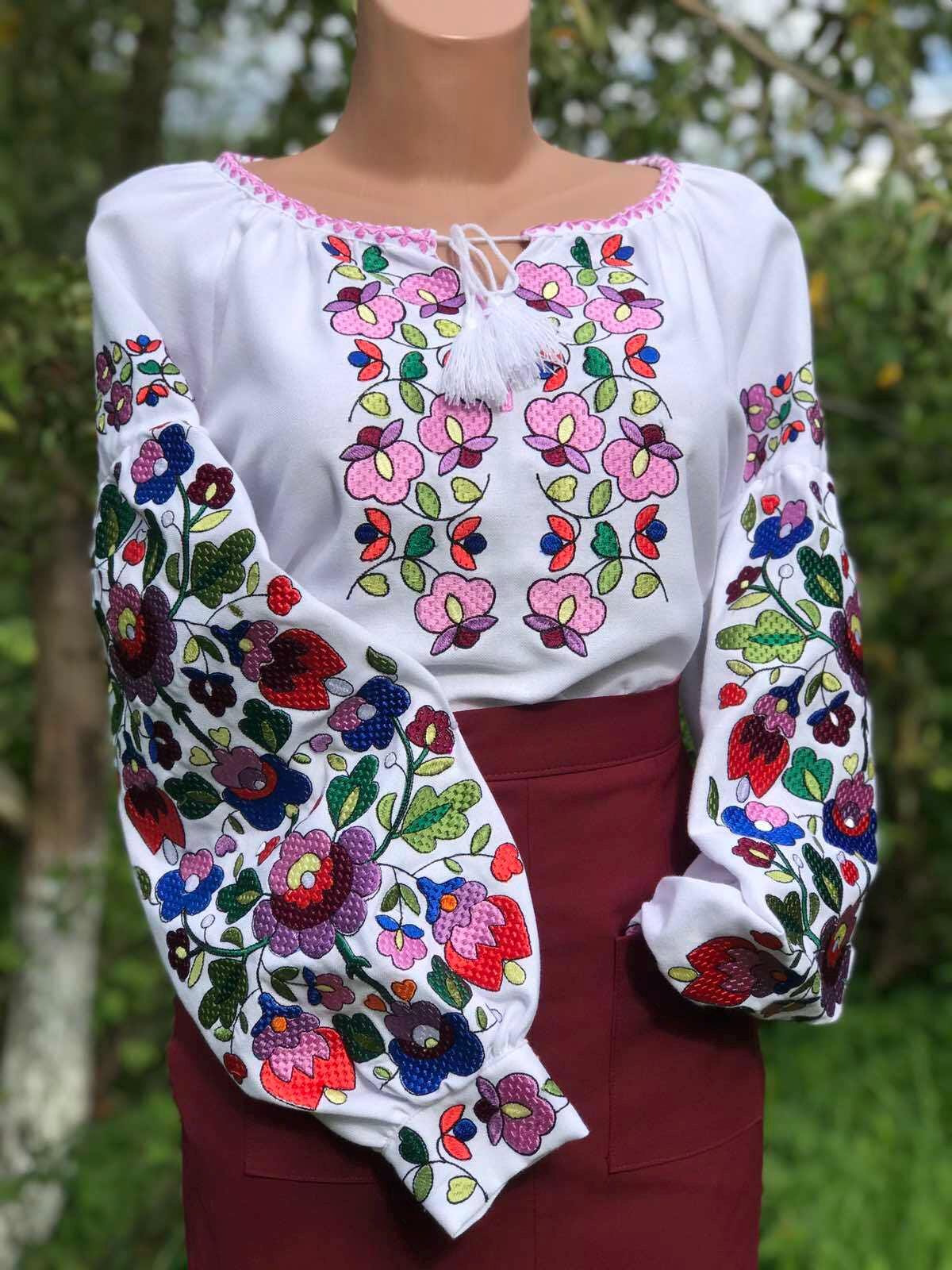 Ukrainian embroidered white blouse with colorful floral patterns on homespun fabric, showcasing traditional folk design.