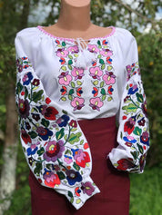 Ukrainian embroidered white blouse with colorful floral patterns on homespun fabric, showcasing traditional folk design.