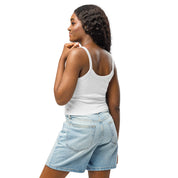 Woman wearing a white micro-rib tank top from the Ukrainian Vibe Trizub Collection paired with denim shorts, showcasing stylish simplicity.