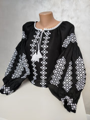 Women's Ukrainian Vyshyvanka embroidered blouse with white folk patterns on black fabric, showcasing traditional craftsmanship.
