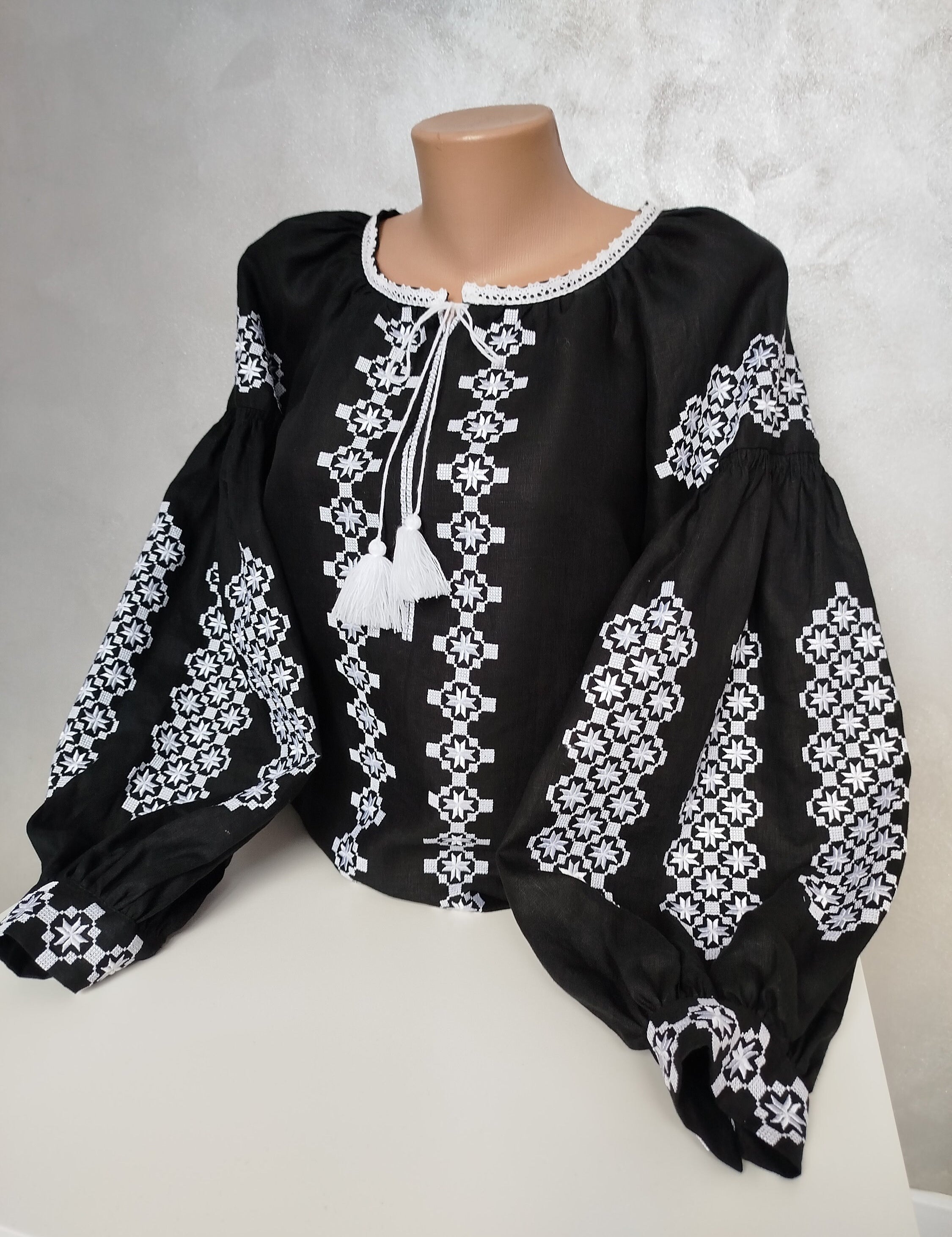 Women's Ukrainian Vyshyvanka embroidered blouse with white folk patterns on black fabric, showcasing traditional craftsmanship.