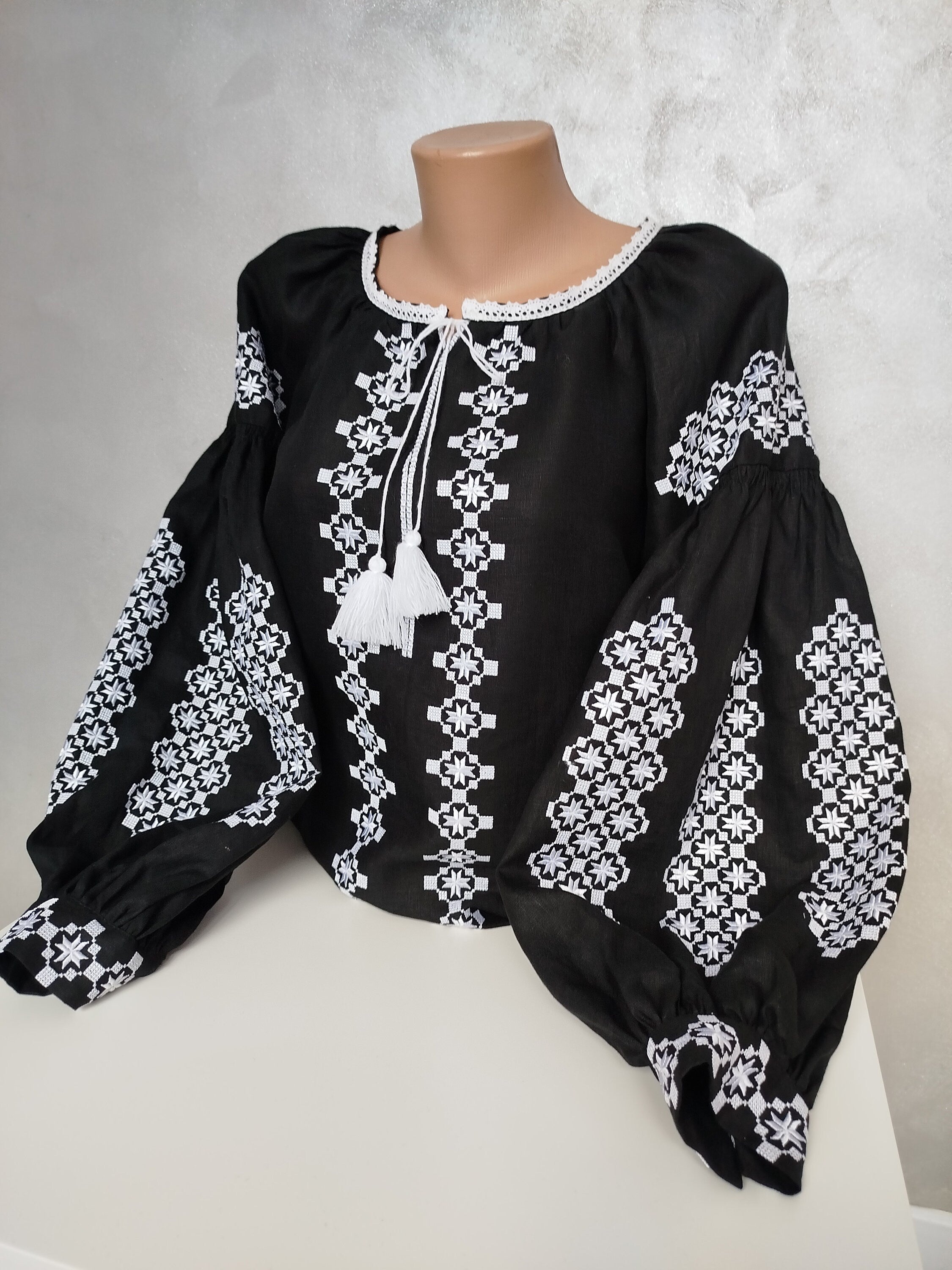 Women's Ukrainian Vyshyvanka embroidered blouse with white folk patterns on black fabric, showcasing traditional craftsmanship.