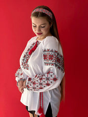 Woman wearing Ukrainian Vyshyvanka, white blouse with red embroidery, traditional folk patterns, cultural fashion.