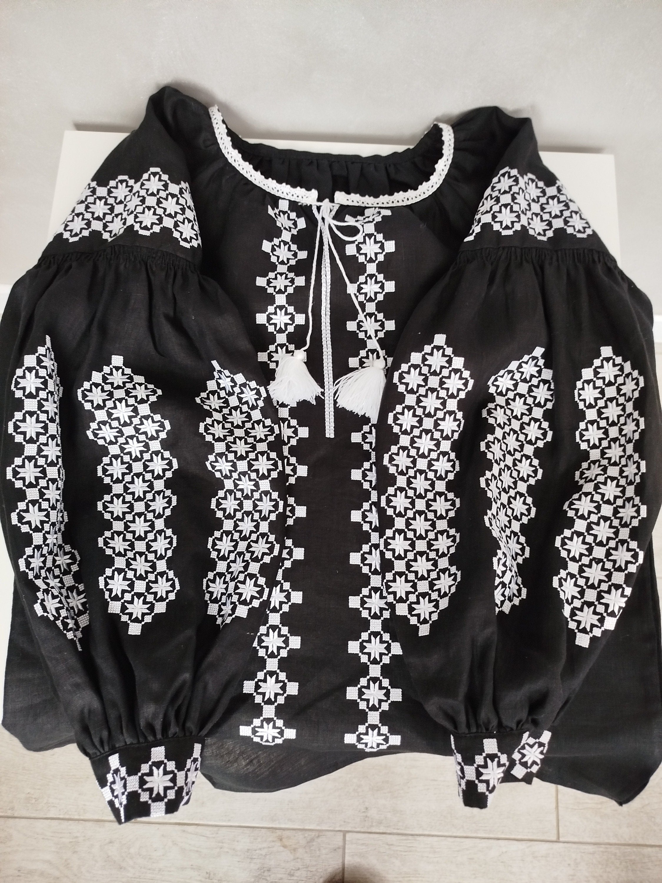 Women's Ukrainian Vyshyvanka blouse with white embroidery on black fabric, showcasing traditional folk design and craftsmanship.