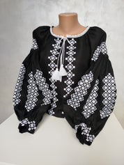 Women's Ukrainian embroidered blouse in black homespun fabric with traditional cross-stitch patterns and silk threads.