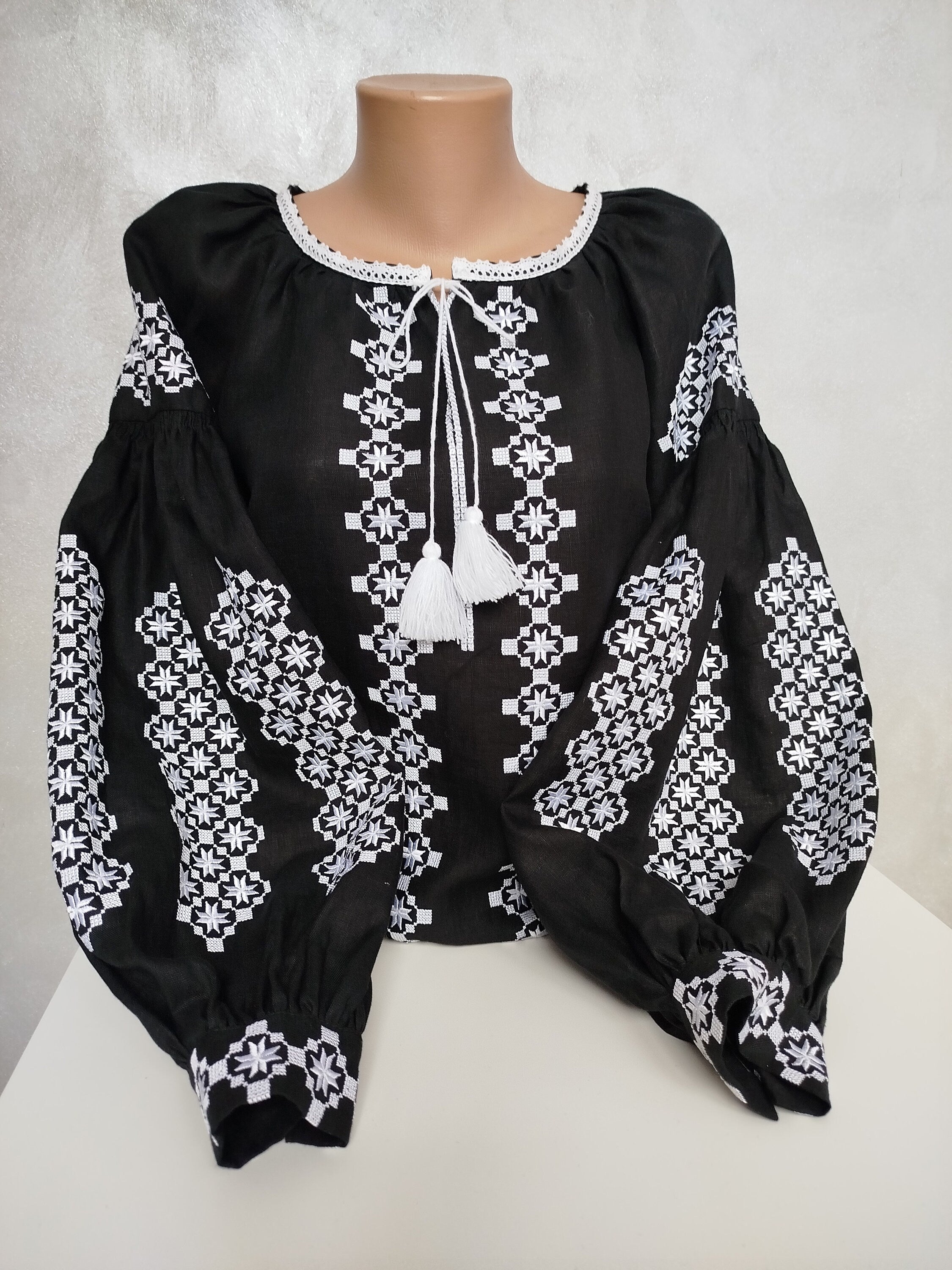 Women's Ukrainian Vyshyvanka with white embroidery on black homespun fabric, featuring traditional folk design and tassels.
