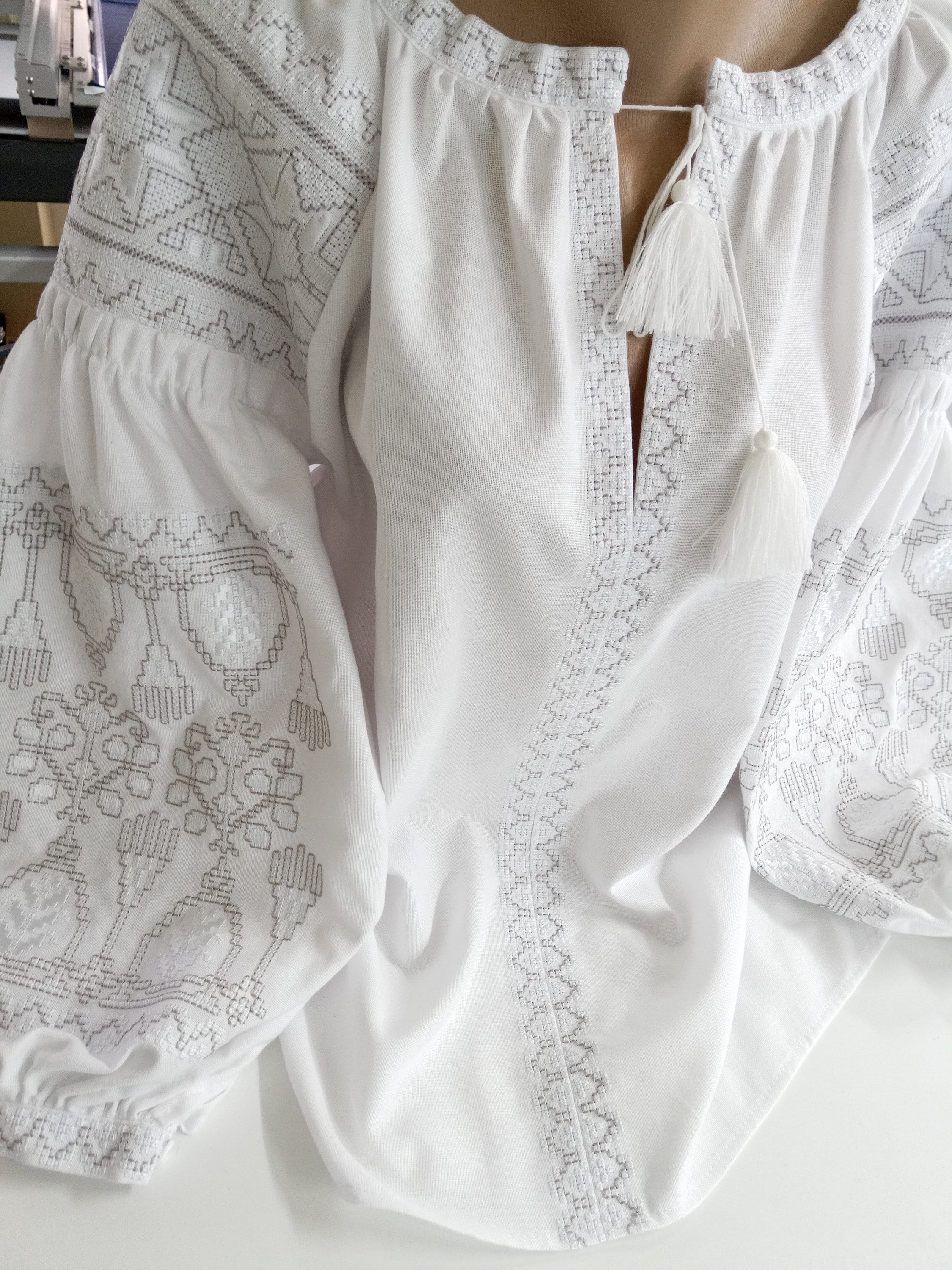 White women's vyshyvanka blouse with Ukrainian cross-stitch embroidery on homespun fabric, showcasing traditional ethnic design.