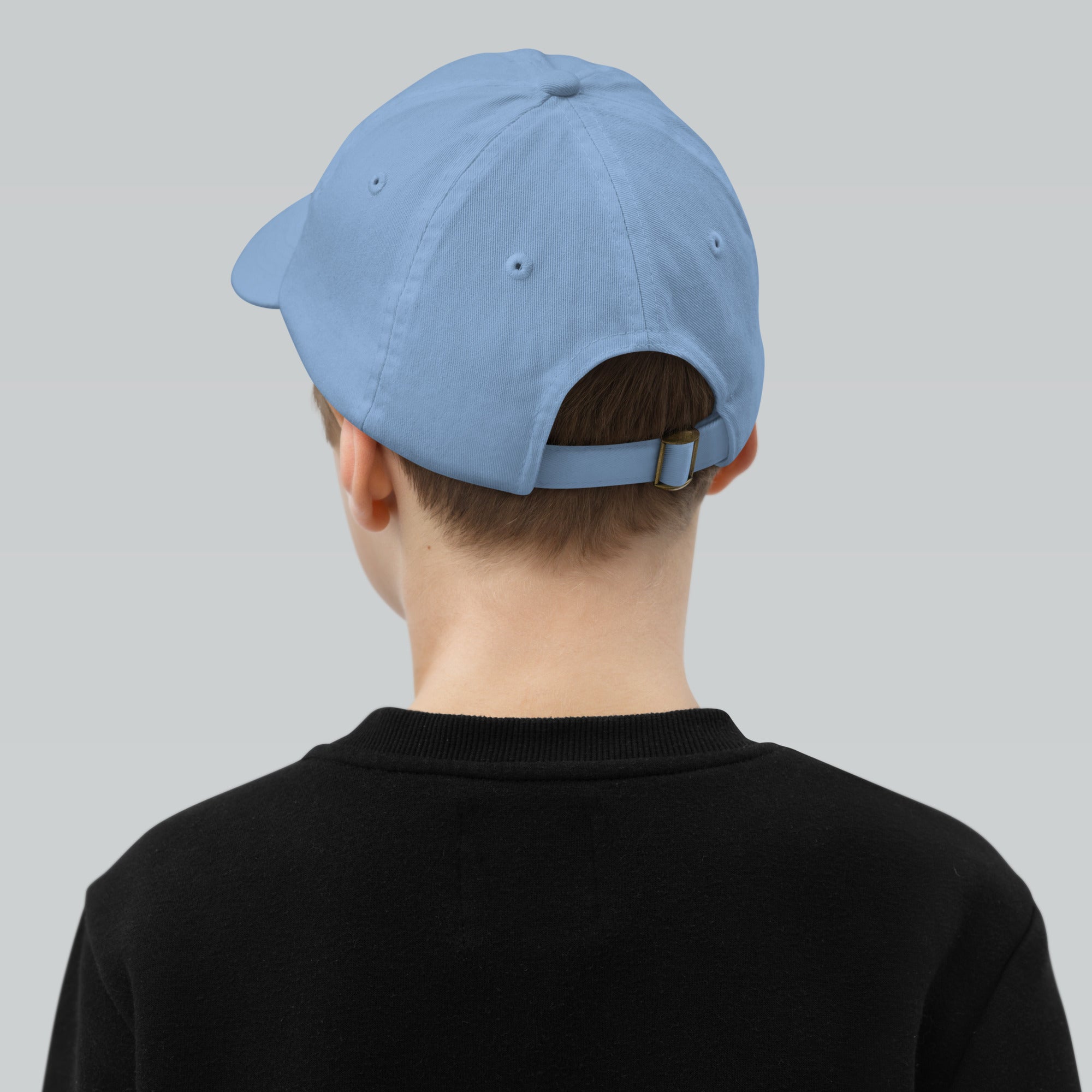 Youth wearing a breathable blue baseball cap with adjustable strap and six ventilation eyelets for active sports and outdoor adventures.