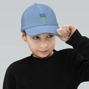 Child wearing a blue baseball cap with Ukrainian Tryzub emblem, featuring breathable fabric and adjustable fit for active kids.