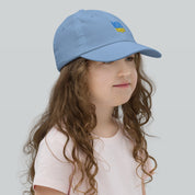 Young girl wearing blue youth baseball cap with Ukrainian Tryzub, ideal for sports and outdoor activities, made from breathable cotton.