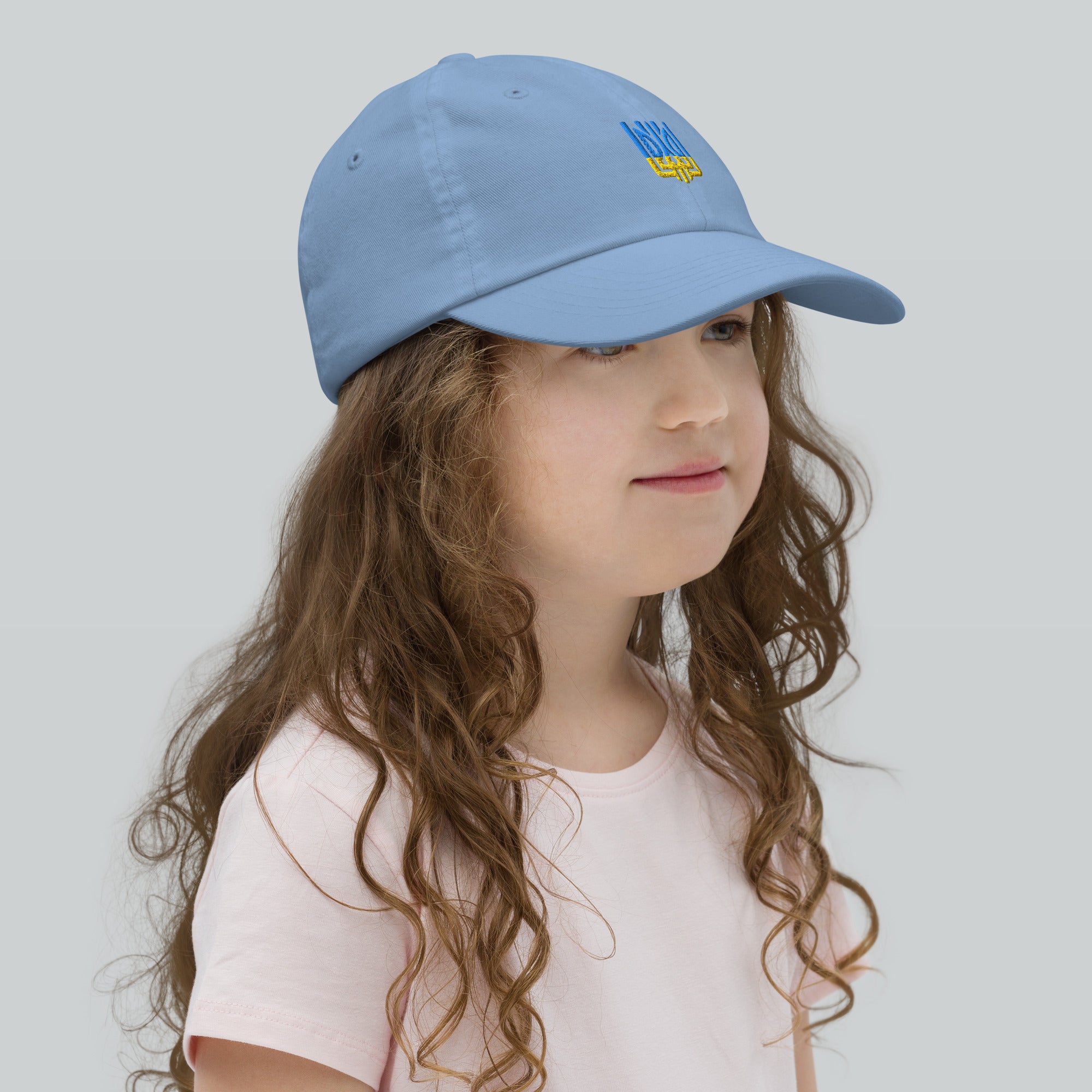 Young girl wearing blue youth baseball cap with Ukrainian Tryzub, ideal for sports and outdoor activities, made from breathable cotton.