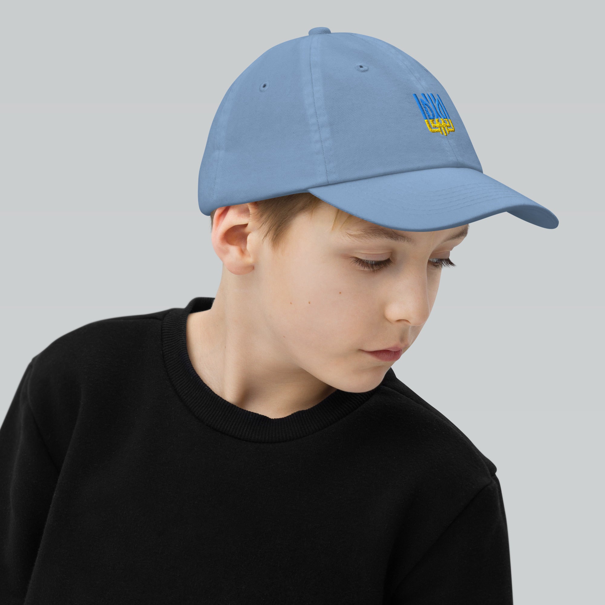 Youth baseball cap with Ukrainian Tryzub, adjustable and breathable, worn by a young boy, ideal for active kids, 100% cotton twill.