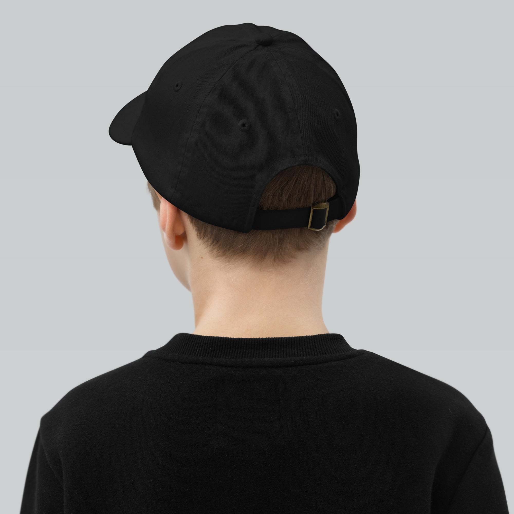 Back view of a child wearing a black adjustable baseball cap with breathable design, perfect for active youth, made from durable bio-washed chino cotton.