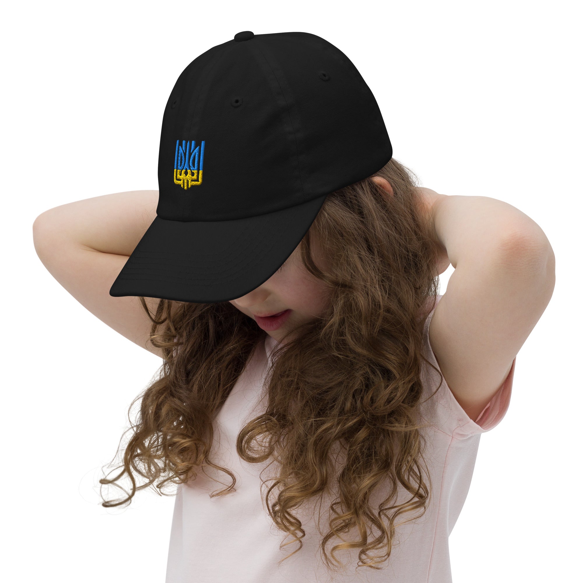 Young girl wearing a youth baseball cap with Ukrainian Tryzub, black, breathable, ideal for active kids, adjustable strap, ventilated design.