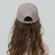 Back view of a gray youth baseball cap on a child, featuring an adjustable strap for a customized fit, made from durable chino cotton twill.