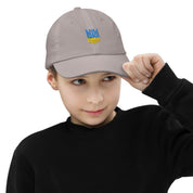 Youth wearing breathable baseball cap with Ukrainian Tryzub emblem, outdoor style, adjustable fit, ideal for sports and adventures