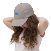 Child wearing a youth baseball cap with Ukrainian Tryzub emblem, adjustable fit, breathable chino cotton twill, ideal for outdoor activities.
