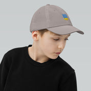 Youth wearing an adjustable baseball cap with Ukrainian Tryzub, perfect for active kids. Made from durable bio-washed chino cotton.