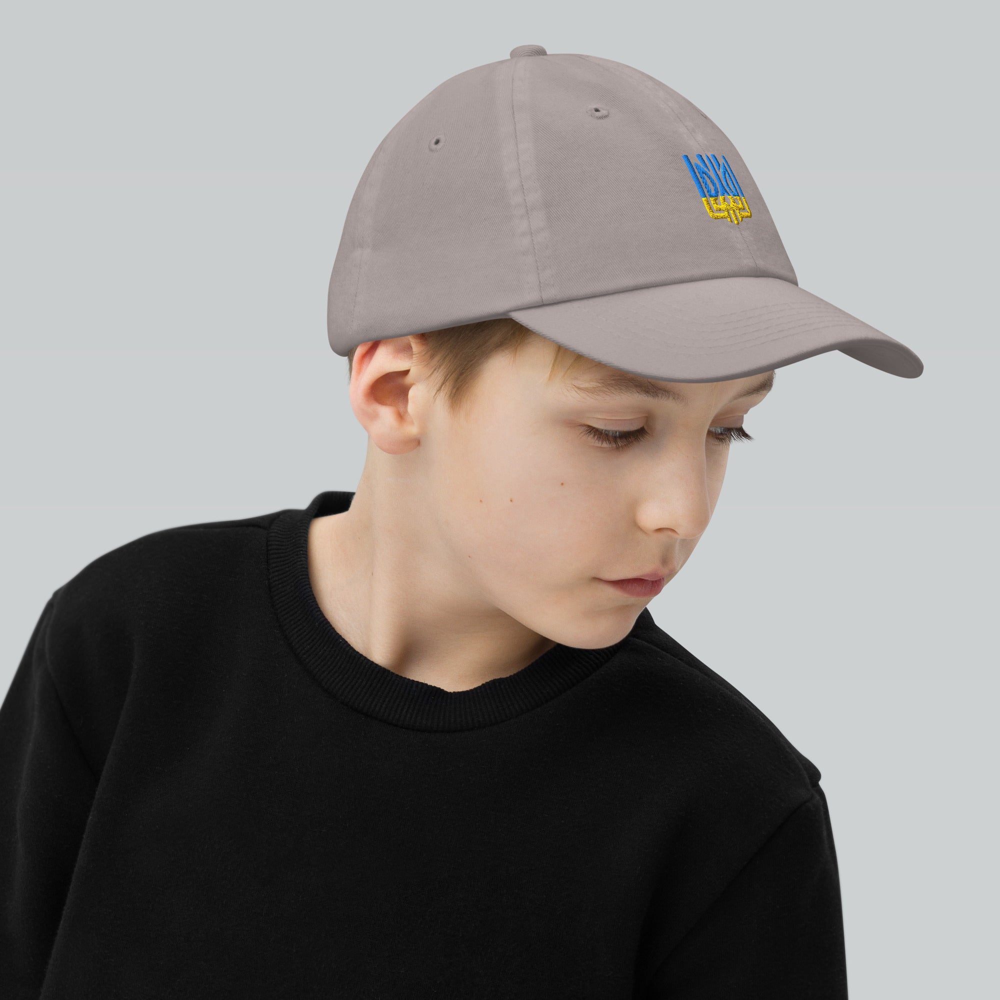 Youth wearing an adjustable baseball cap with Ukrainian Tryzub, perfect for active kids. Made from durable bio-washed chino cotton.