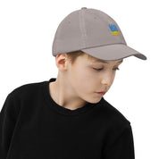 Youth wearing baseball cap with Ukrainian Tryzub emblem, breathable and adjustable, ideal for sports and outdoor activities.