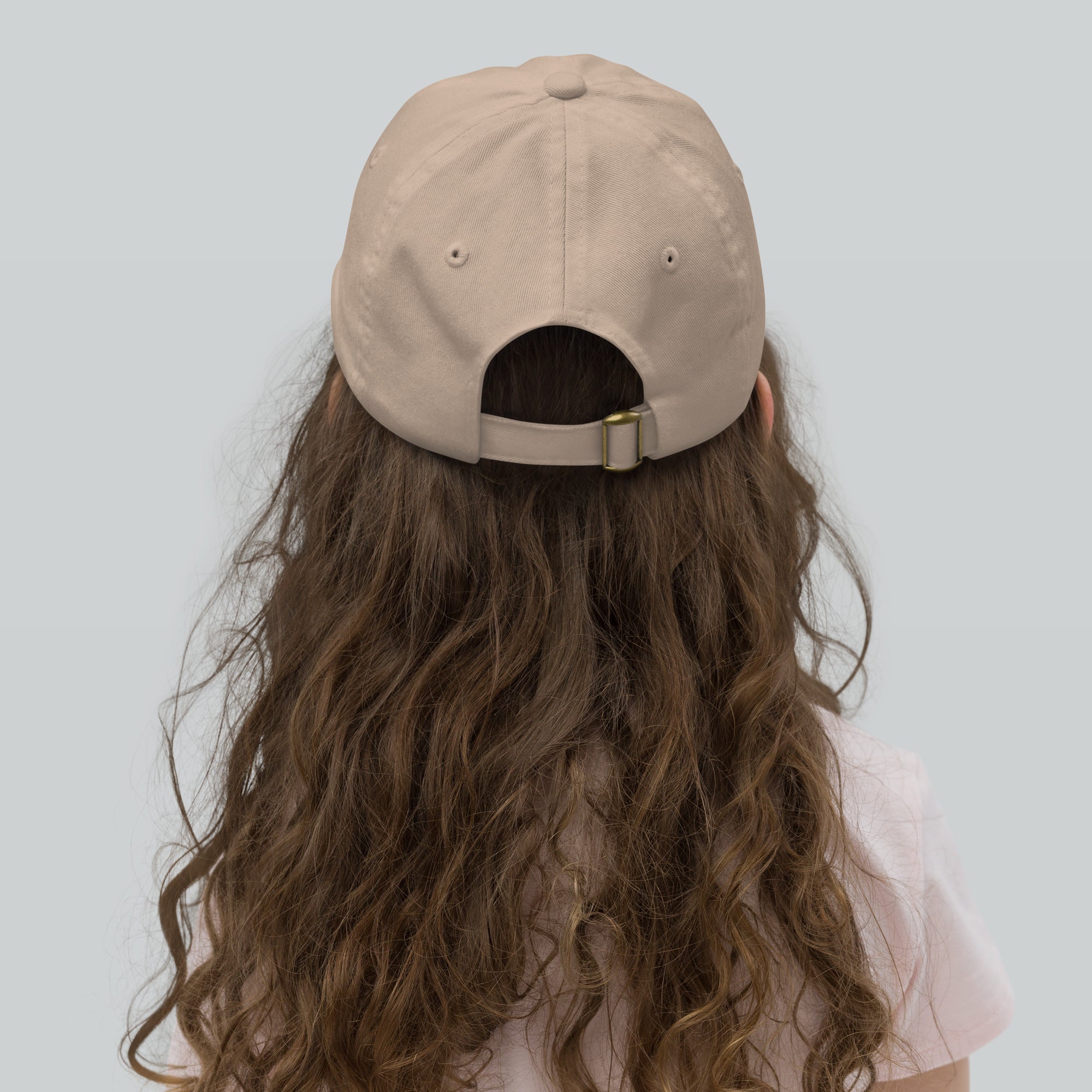 Child wearing beige youth baseball cap with adjustable strap for a secure fit. Ideal for active kids' outdoor adventures.