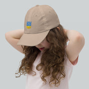 Youth baseball cap with Ukrainian Tryzub on a girl, beige, chino cotton, adjustable strap, breathable, stylish, for active kids.