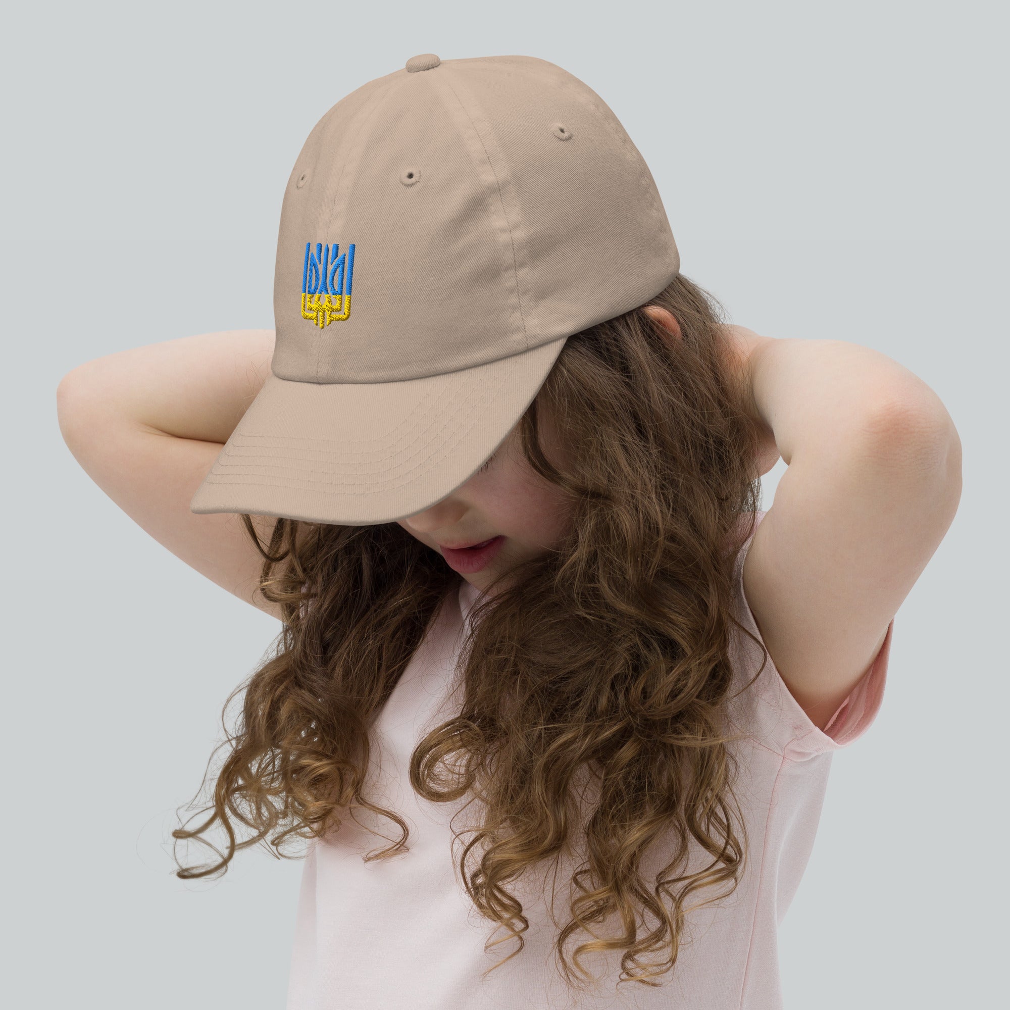Youth baseball cap with Ukrainian Tryzub on a girl, beige, chino cotton, adjustable strap, breathable, stylish, for active kids.